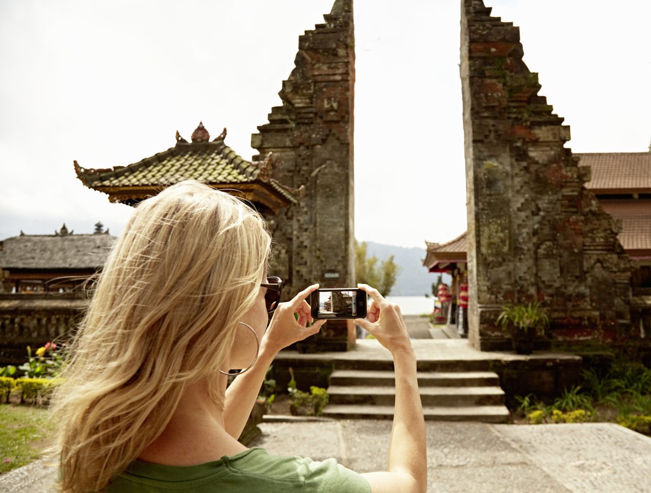 Woman taking a picture of a temple in Bali, Indonesia